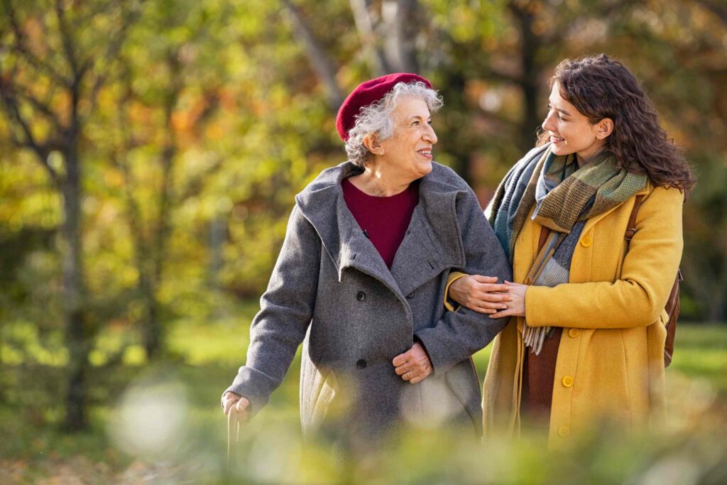 An older woman smiling and walking confidently, arm linked with her adult daughter.